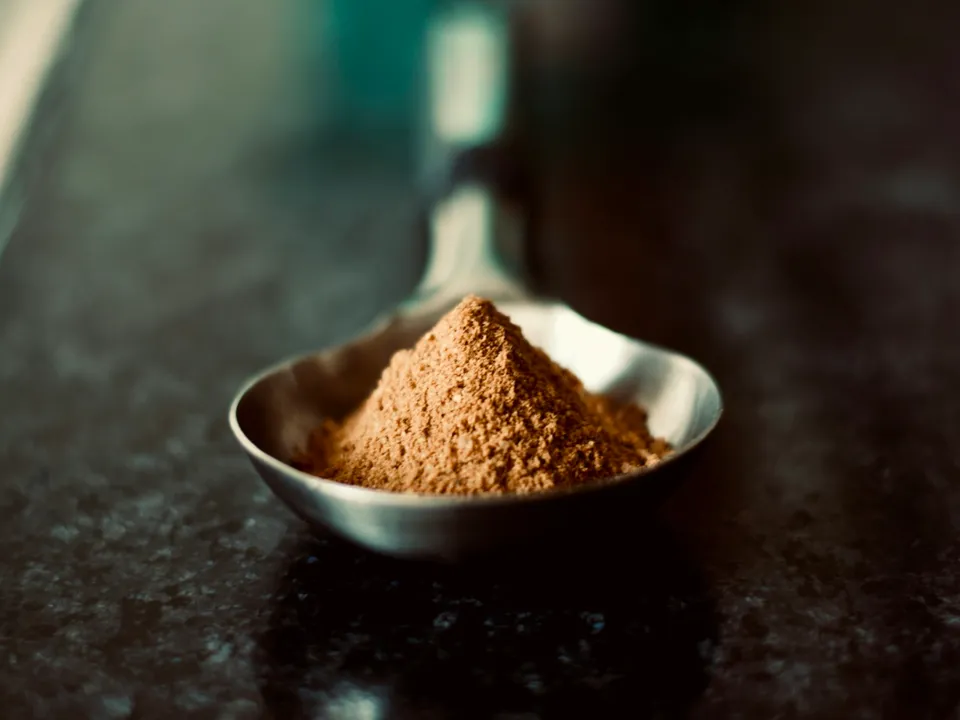 A spoon heaped with cocoa powder in low light.